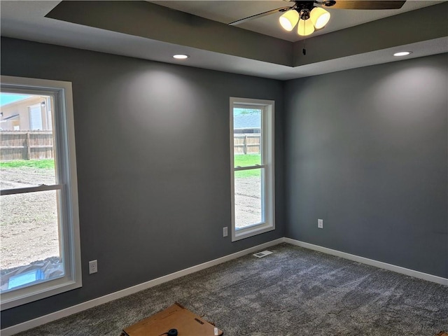 449 E Market St, Warrensburg, MO 64093 - empty room featuring dark colored carpet, a ceiling fan, and a raised ceiling