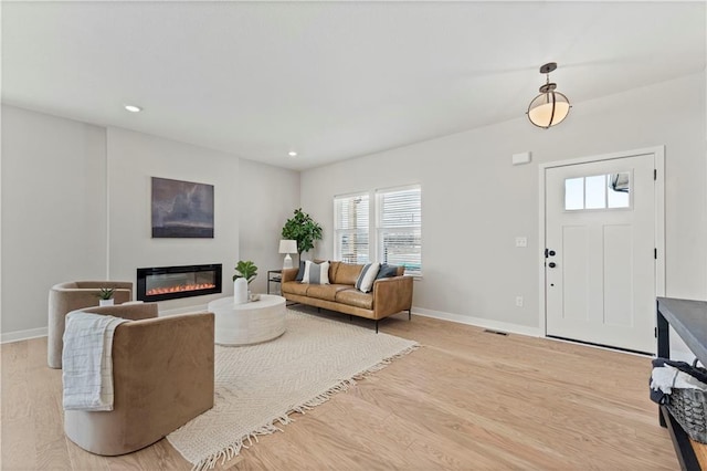 402 Woodview Dr, Raymore, MO 64083 - living area with a glass covered fireplace, baseboards, light wood-style flooring, and recessed lighting