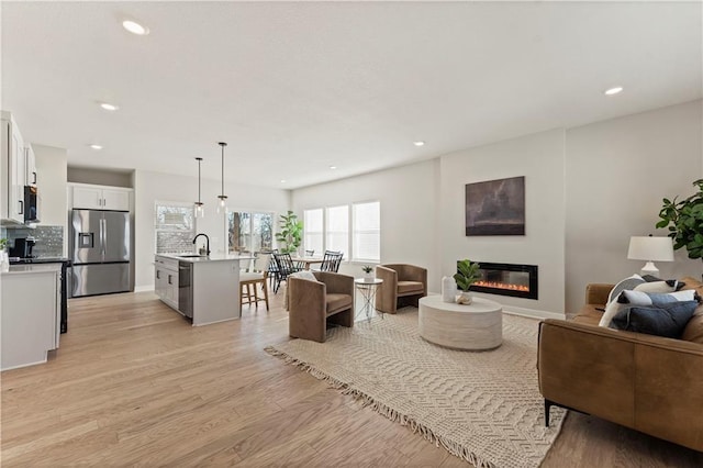 402 Woodview Dr, Raymore, MO 64083 - living room featuring a glass covered fireplace, light wood-type flooring, and recessed lighting
