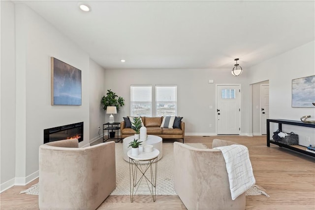 402 Woodview Dr, Raymore, MO 64083 - living room featuring a glass covered fireplace, baseboards, recessed lighting, and light wood-style flooring