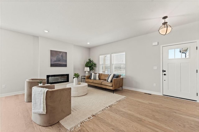 402 Woodview Dr, Raymore, MO 64083 - living area with light wood-style flooring, baseboards, a glass covered fireplace, and recessed lighting