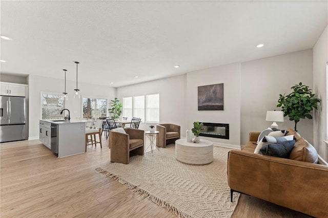 402 Woodview Dr, Raymore, MO 64083 - living area featuring a glass covered fireplace, light wood finished floors, recessed lighting, and baseboards