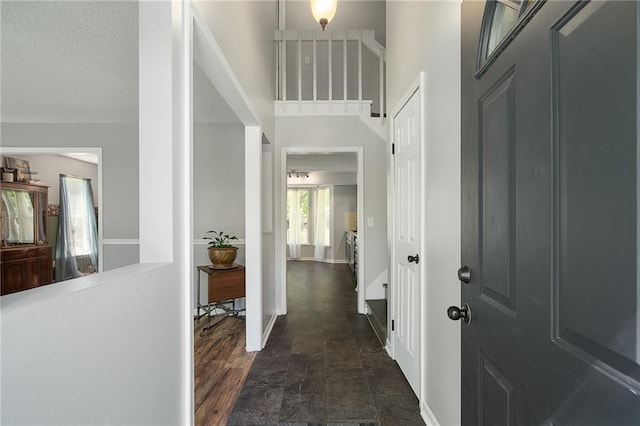 foyer entrance featuring dark stone finish flooring, a textured ceiling, and baseboards
