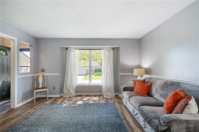 living room featuring a textured ceiling, wood finished floors, and baseboards