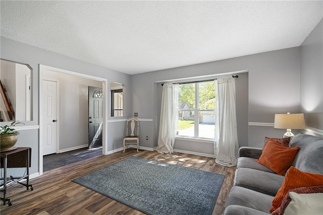 living area featuring arched walkways, a textured ceiling, wood finished floors, and baseboards