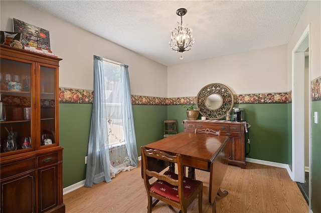 dining room featuring a chandelier, light wood finished floors, a textured ceiling, and baseboards