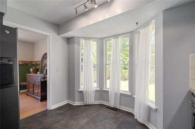 unfurnished dining area featuring a textured ceiling and baseboards