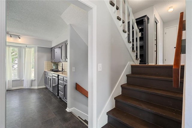 stairs featuring a textured ceiling and baseboards