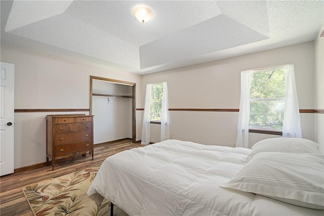 bedroom with a closet, wood finished floors, and baseboards