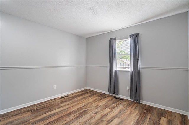 unfurnished room featuring wood finished floors, a textured ceiling, and baseboards