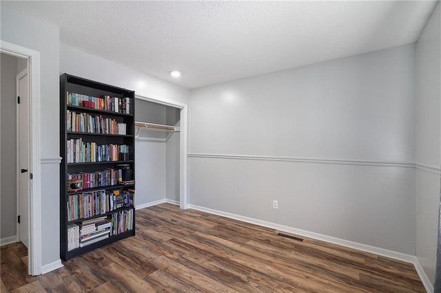 unfurnished bedroom featuring dark wood-style flooring, baseboards, a closet, a textured ceiling, and recessed lighting