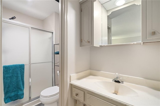 bathroom with a stall shower, toilet, and vanity