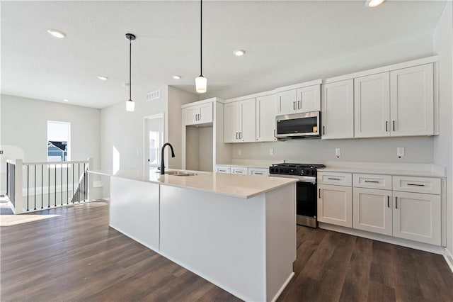 501 Woodview Dr, Raymore, MO 64083 - kitchen with stainless steel appliances, a sink, dark wood finished floors, recessed lighting, and light countertops
