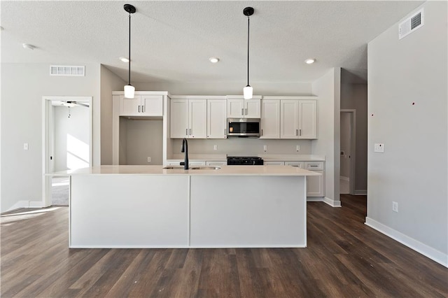 501 Woodview Dr, Raymore, MO 64083 - kitchen with stainless steel microwave, a sink, stove, white cabinets, and dark wood finished floors