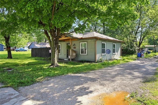 bungalow with gravel driveway and a front lawn