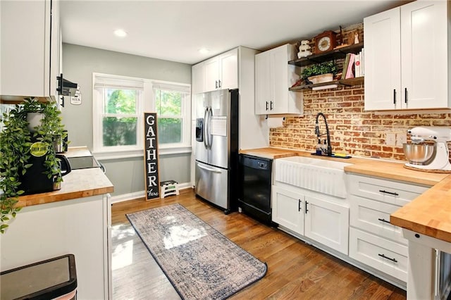 kitchen featuring wood counters, stainless steel fridge with ice dispenser, black dishwasher, a sink, and open shelves
