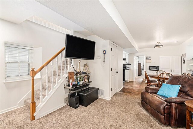 carpeted living area featuring stairs and baseboards