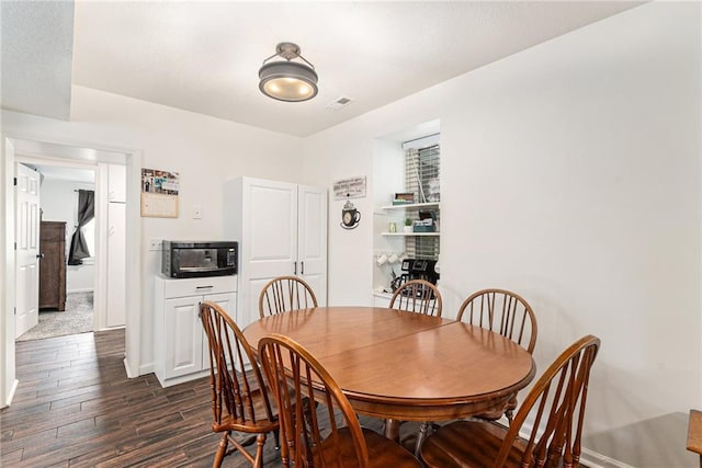 dining area with dark wood-style flooring and baseboards