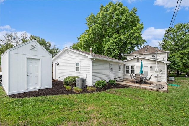 back of property featuring cooling unit, a lawn, a patio area, and an outdoor structure