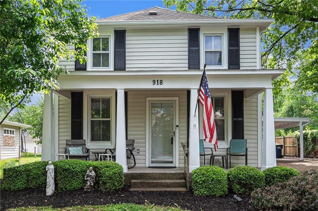 traditional style home with a porch, fence, and a shingled roof