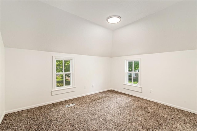 carpeted spare room featuring vaulted ceiling, plenty of natural light, and baseboards