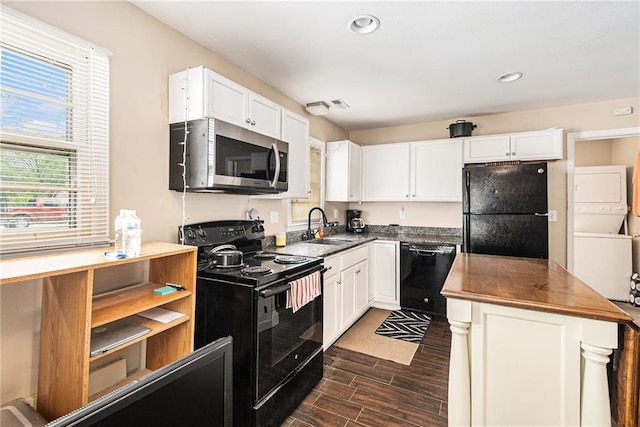 kitchen featuring black appliances, estacked washer and dryer, a sink, dark wood finished floors, and white cabinets
