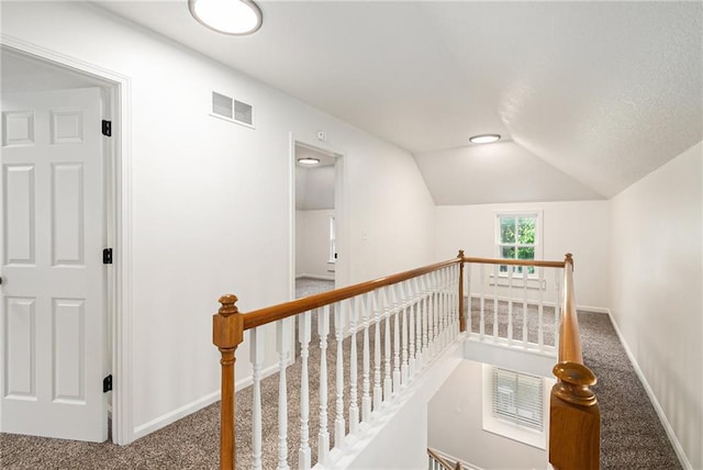 corridor with an upstairs landing, carpet floors, vaulted ceiling, and baseboards