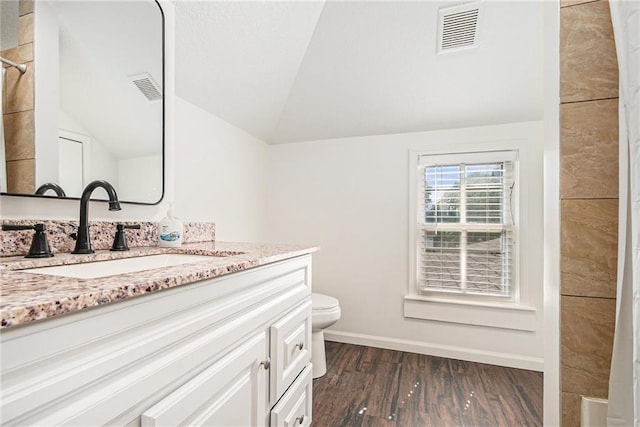 full bathroom featuring vaulted ceiling, wood finished floors, vanity, baseboards, and toilet
