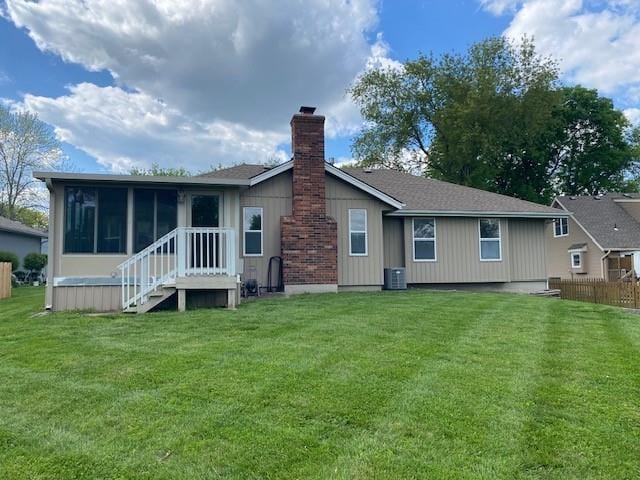 rear view of property featuring a sunroom, central AC unit, and a chimney