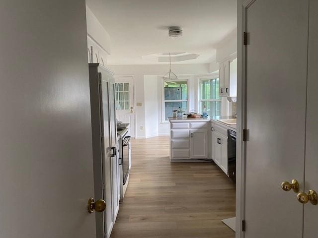 kitchen with dishwasher, white cabinets, wood finished floors, light countertops, and decorative light fixtures