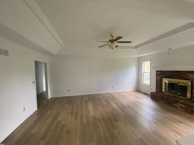 unfurnished living room with a raised ceiling, wood finished floors, a ceiling fan, and baseboards