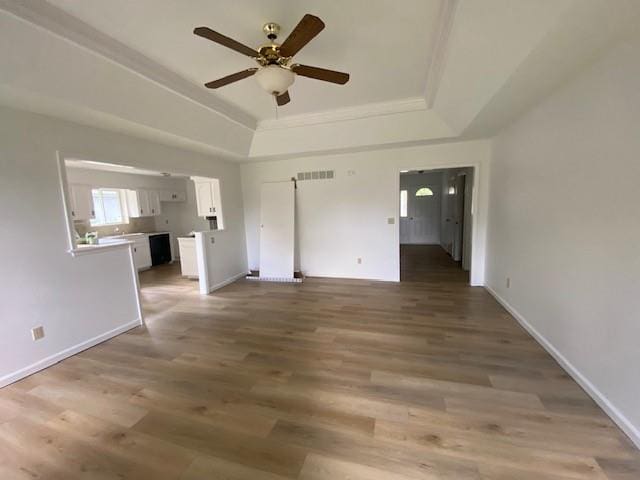 unfurnished bedroom with a raised ceiling, wood finished floors, baseboards, and ceiling fan