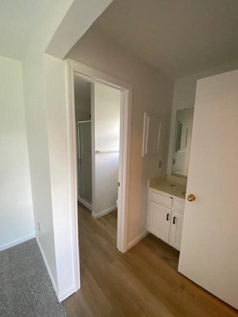 full bath with a shower stall, vanity, wood finished floors, toilet, and baseboards