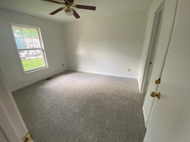 unfurnished room featuring carpet, a ceiling fan, and baseboards