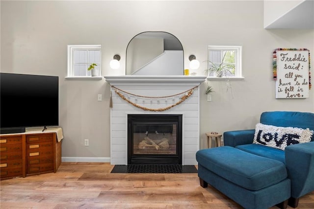 sitting room with wood finished floors, a fireplace with flush hearth, and baseboards