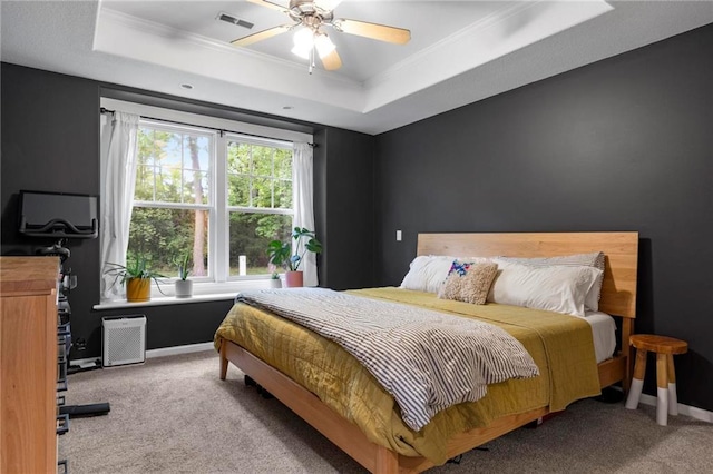 bedroom featuring a raised ceiling, carpet, crown molding, baseboards, and a ceiling fan