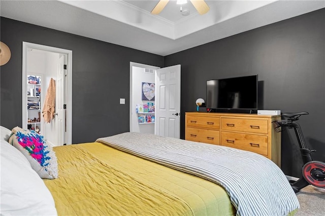 carpeted bedroom with a raised ceiling, ornamental molding, and a ceiling fan