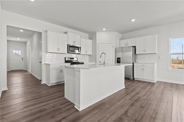 kitchen with stainless steel appliances, a sink, tasteful backsplash, white cabinets, and recessed lighting