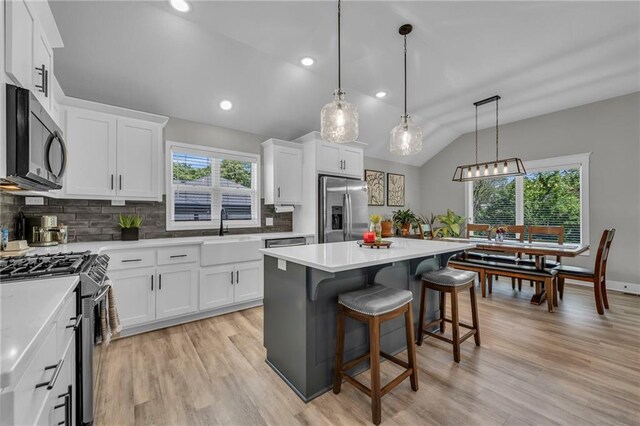 18235 NW 127th St, Platte City, MO 64079 - kitchen with appliances with stainless steel finishes, vaulted ceiling, backsplash, white cabinetry, and light countertops