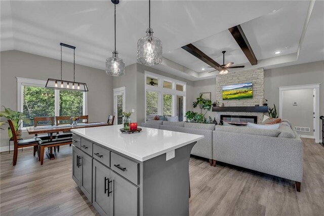18235 NW 127th St, Platte City, MO 64079 - kitchen with gray cabinetry, ceiling fan, a stone fireplace, a center island, and healthy amount of natural light