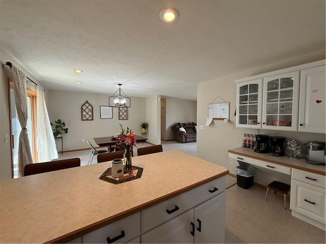 727 Serenity Loop, Maryville, MO 64468 - kitchen featuring glass insert cabinets, a chandelier, light countertops, white cabinets, and a textured ceiling