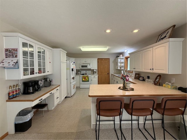 727 Serenity Loop, Maryville, MO 64468 - kitchen with white appliances, a peninsula, a kitchen breakfast bar, light countertops, and recessed lighting