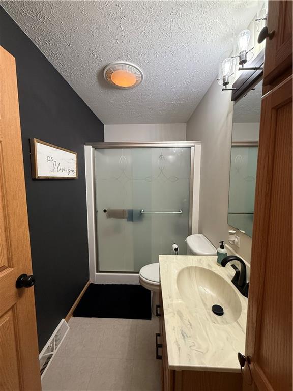 727 Serenity Loop, Maryville, MO 64468 - full bath featuring a textured ceiling, a stall shower, vanity, and toilet