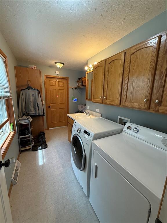 727 Serenity Loop, Maryville, MO 64468 - washroom featuring cabinet space, washing machine and dryer, a textured ceiling, and light flooring