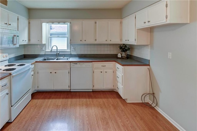 kitchen featuring white appliances, a sink, light wood finished floors, white cabinets, and tasteful backsplash