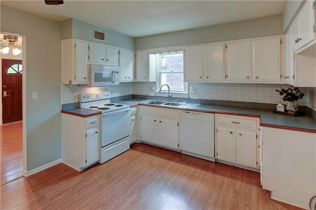 kitchen with white appliances, a sink, light wood-style floors, and white cabinetry