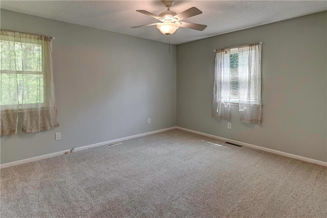 carpeted empty room with ceiling fan, baseboards, and a textured ceiling