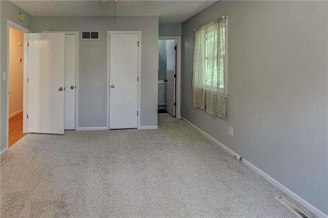 unfurnished bedroom with carpet flooring, baseboards, connected bathroom, and a closet