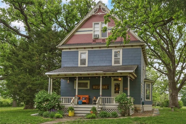 victorian house featuring covered porch, a front yard, and cooling unit