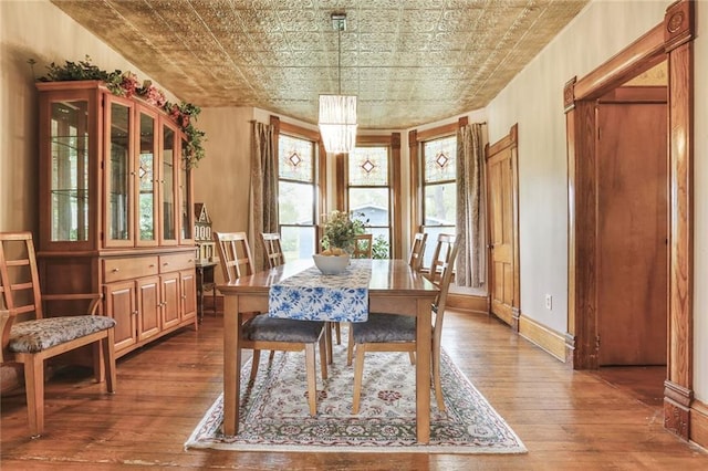 dining room with hardwood / wood-style floors, an ornate ceiling, and baseboards
